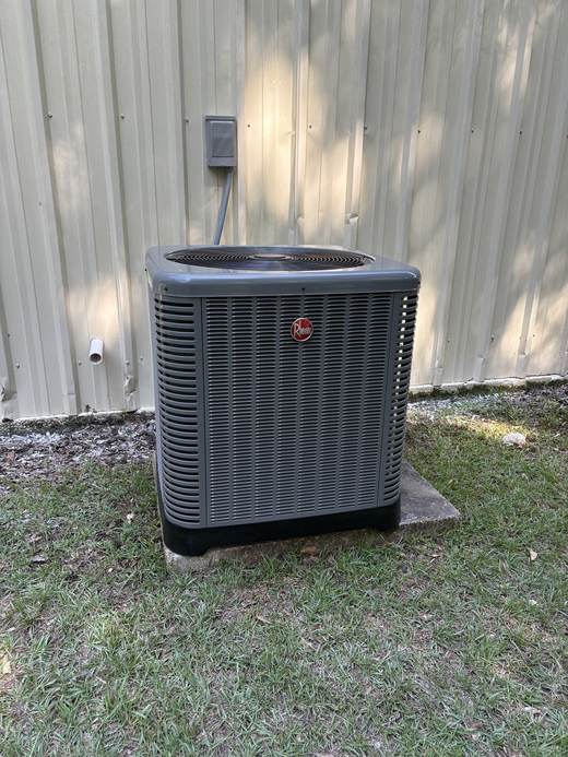 Rheem AC condenser unit installed against metal siding